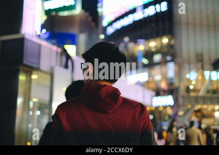 Giovane uomo che cammina di fronte al grande magazzino città di notte Foto Stock