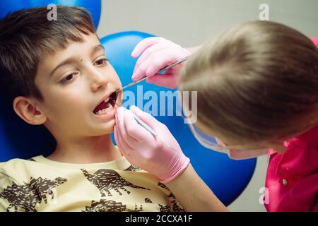 Ragazzo adolescente paziente presso il dentista. Un ragazzo con problema denti seduti in un riunito dentale. Foto Stock