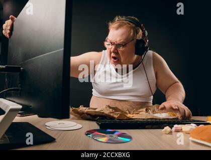 uomo arrabbiato e furioso seduto con un computer a casa. primo piano vista laterale foto. sfondo nero isolato. concetto di irritazione. concetto di degrado Foto Stock