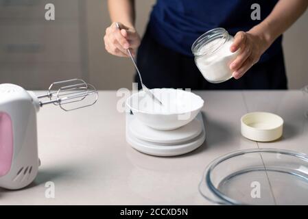 Donna che misura gli ingredienti di cottura su una piccola scala della cucina mentre fare biscotti in cucina a casa closeup Foto Stock