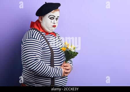 clown infelice con fiori in mani che vengono bullonati, offesi da qualcuno. primo piano ritratto, copia spazio. luogo per testo, annuncio , Foto Stock