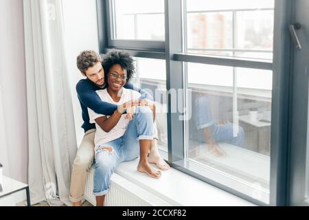 Piuttosto giovane vicino alla finestra. interracial giovane. così felice Foto Stock