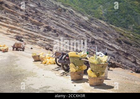 CESTINO DI ZOLFO SUL VULCANO KAWAH IJEN. Cestino pesante caricato da pezzi di zolfo naturale da trasportare dai minatori dalla miniera del cratere. Operazione manuale di estrazione dello zolfo ad alta intensità di manodopera nel vulcano Kawah Ijen. Destinazione di viaggio popolare in Java Indonesia Foto Stock