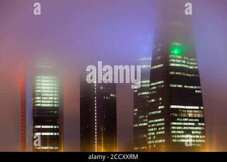 Cuatro Torres Business Area edificio illuminato in nebbia serale, Madrid, Spagna Foto Stock