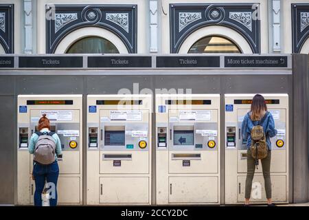 I passeggeri che acquistano i biglietti del treno dalle macchine della stazione di Londra Paddington Foto Stock