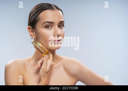 Bella donna ben curata che tiene un prodotto di bellezza Foto Stock