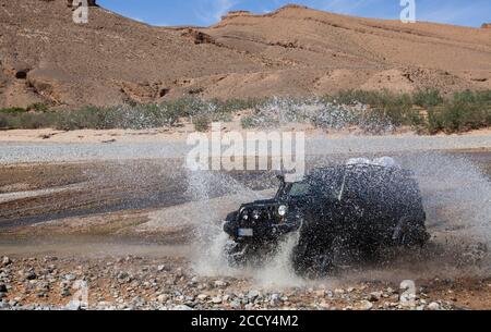 Un veicolo fuoristrada attraversa un fiume nel Medio Atlante, Marocco Foto Stock