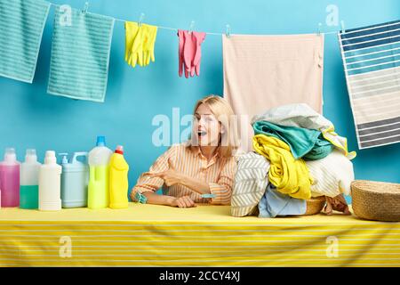 Allegra donna bionda felice in camicia a righe che mostra il liquido di lavaggio in bottiglie, concetto di raccomandazione. Advise.Hury fino ad acquistare buon detersivo.master cl Foto Stock