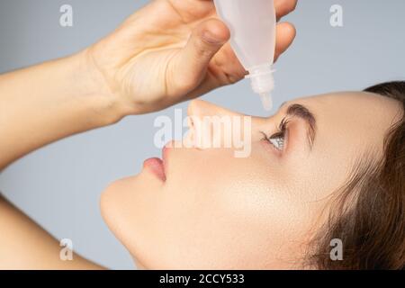 Donna che applica un farmaco liquido per gli occhi Foto Stock