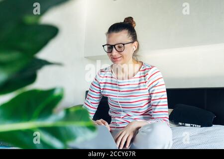 giovane tutor donna in cuffia con videochiamata che lavora su laptop a casa a distanza. formazione online a distanza in quarantena auto isolamento. studente tal Foto Stock