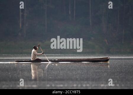 Uomo in canoa dugout su un lago, Kisoro, Uganda, Africa orientale Foto Stock