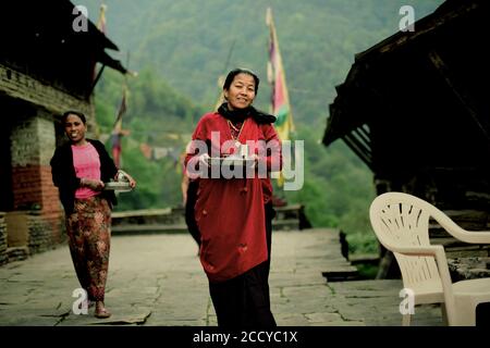 Gli abitanti del villaggio portano pasti per i visitatori al villaggio di Sidhane nella regione montana di Panchase, Kaski, Gandaki Pradesh, Nepal. Foto Stock