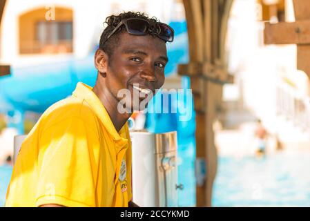 Egitto, Hurghada - ritratto sorridente del personale egiziano del bagnino dell'hotel nell'area della piscina sullo sfondo Foto Stock