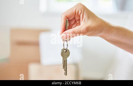 Mano di riproprietario o proprietario che tiene le chiavi alla nuova casa dopo il passaggio Foto Stock