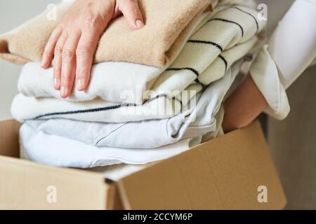Donna impacchi i vestiti in una scatola mobile per un vestito donazione o per il trasferimento Foto Stock