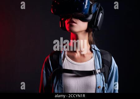 Ritratto di una giovane ragazza che indossa un dispositivo VR sugli occhi. Isolato su sfondo nero, UV Foto Stock