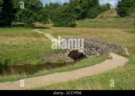 Uno dei rustici ponti in pietra sul fiume Skell, patrimonio dell'umanità reale di Studley, che fa parte della Seven Bridges Valley Walk Foto Stock