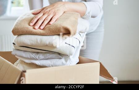 Donna confeziona i vestiti per una donazione di vestiti in una scatola o le stidie in su Foto Stock