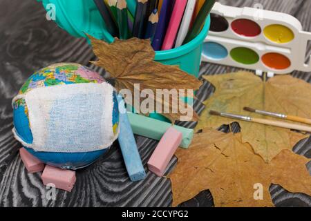 Globo con maschera medica. Acquerelli, pastelli e matite nelle vicinanze. Anno accademico durante l'epidemia. Foto Stock