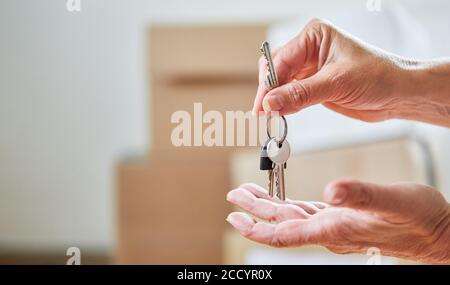 Le mani di coppia tengono le chiavi dalla casa dopo il movimento dentro nuova casa Foto Stock