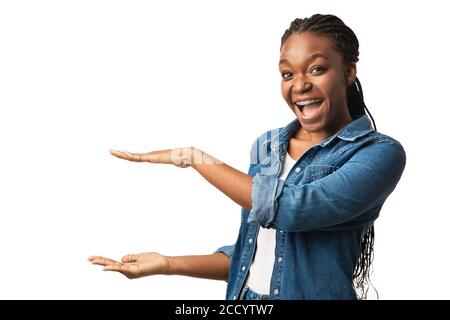 Joyful Black Girl in parentesi graffe che tiene invisibile oggetto, Studio Shot Foto Stock