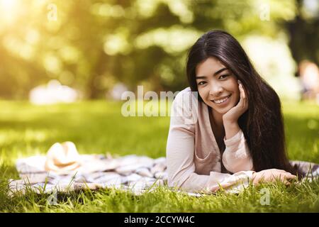 Esterno Ritratto di bella ragazza asiatica rilassante su Plaid in Parcheggio Foto Stock