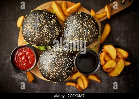 Hamburger neri e patatine fritte con salsa Foto Stock