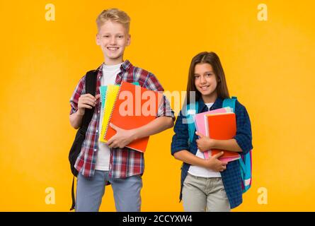 Ragazzi sorridenti che posano con libri di testo in studio Foto Stock