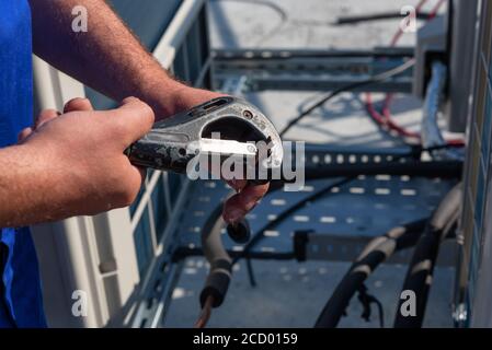 Il tecnico HVAC sta lavorando sulle unità di climatizzazione su un tetto di un nuovo edificio industriale. Il tecnico sta installando il condizionatore d'aria.cop di taglio Foto Stock