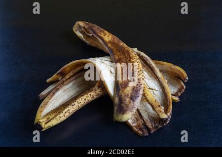 Foto dettagliata scartata buccia di banana su sfondo nero. La buccia di banane sopramature con macchie marroni. Rifiuti alimentari. Primo piano. Messa a fuoco selettiva. Foto Stock