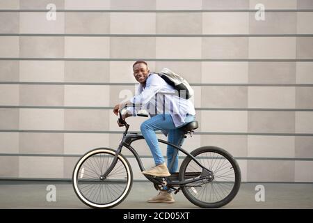 Ritratto di gioioso ragazzo nero con bicicletta vicino muro di mattoni esterno Foto Stock