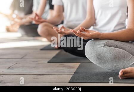 Gruppo di persone irriconoscibili meditando in posizione Lotus e mostrando Gesti Mudra Foto Stock