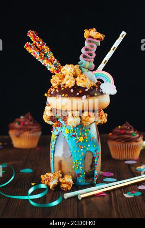 Frullato di cioccolato con ciambelle e popcorn al caramello sullo sfondo rustico di legno; fuoco selettivo. Foto Stock