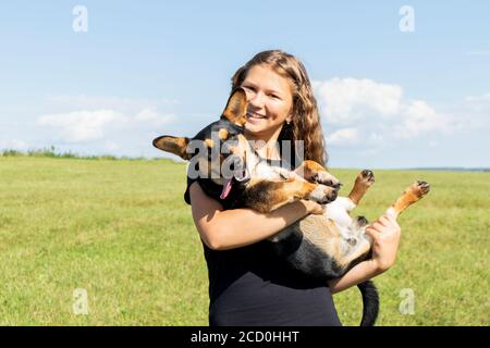 Giovane ragazza con capelli ricci con il suo cucciolo in braccio. Ragazza che tiene un cane. Foto Stock