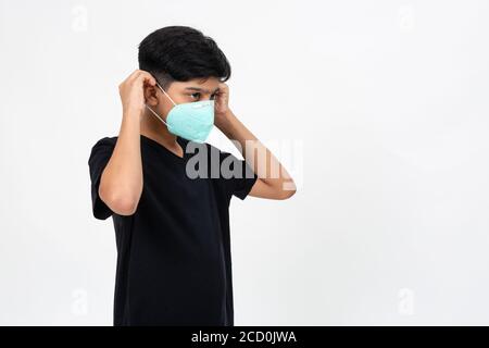 Il giovane ragazzo indiano indossa una maschera facciale per la protezione contro Covid-19. Cute teenager mette sulla maschera Foto Stock