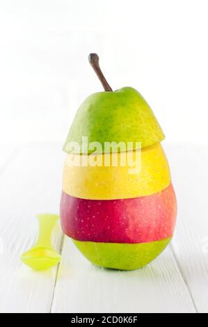 Concetto naturale di alimenti per bambini. Frutta fresca a forma di piramide pezzi di mele e pere vicino baby cucchiaio su sfondo bianco di legno con spazio copia. Selettivo Foto Stock