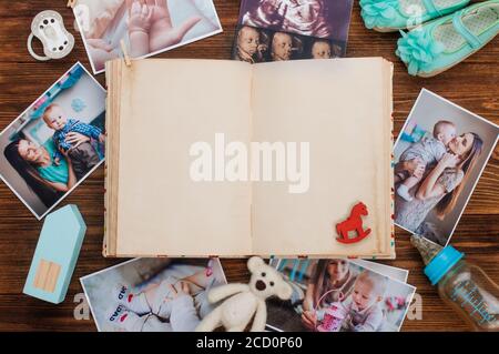 Apri album vintage con foto e accessori per madre e bambino su sfondo rustico in legno. Spazio vuoto per il testo. Vista dall'alto, disposizione piatta. Foto Stock