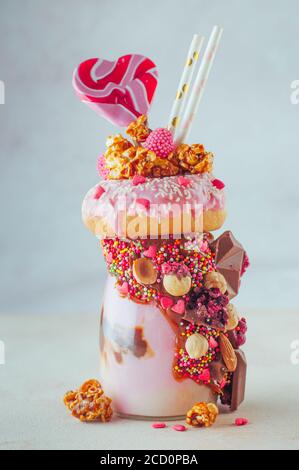 Raspberry Freak agita con ciambella, popcorn e dolci su sfondo grigio; fuoco selettivo. Foto Stock