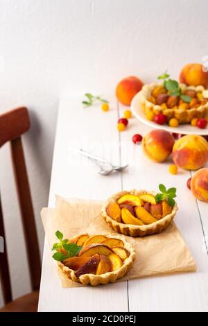 Torta aperta di pasta frolla con pesche, clafoutis di pesca su tavola bianca Foto Stock