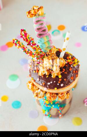 Concetto di festa dei bambini: Vista dall'alto del frana di cioccolato con ciambelle e popcorn al caramello sul tavolo della festa; fuoco selettivo. Foto Stock