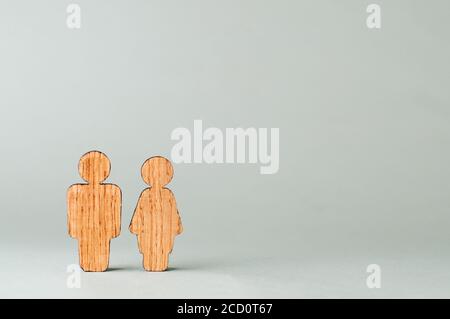 Figure in legno di uomo e donna su sfondo grigio con spazio vuoto per il testo. Foto Stock