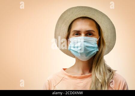 ritratto di giovane donna che indossa una maschera medica protettiva su sfondo arancione pastello. concetto pandemico coronavirus Foto Stock