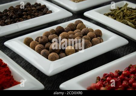 Allspice. Spezie colorate in ciotole bianche Condimenti per cucinare. Erbe e spezie naturali. Foto Stock