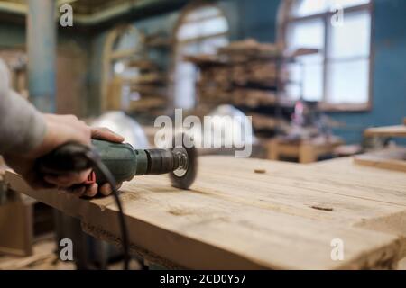 Lavorazione a mano con una spazzolatrice per levigare un pezzo di legno. Foto Stock