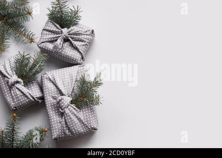 Regali di Natale avvolti in tessuto rosso e grigio. Zero sprechi. Natale. Stile Furoshiki Giapponese. Vista dall'alto. Disposizione piatta. Foto Stock