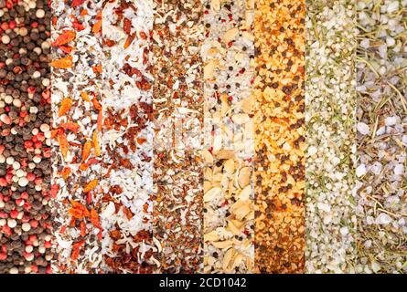 La consistenza delle spezie colorate e delle erbe si mescolano. Gruppo di spezie colorate. Collage di erbe e spezie diverse Peperoni, sale marino, verdure secche, Oregano, Foto Stock