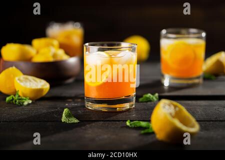 Foto di tè freddo al limone su sfondo scuro. Una rinfrescante bevanda estiva fatta di limone spremuto a mano fresco mescolato con tè nero freddo, ghiaccio e zucchero. R Foto Stock