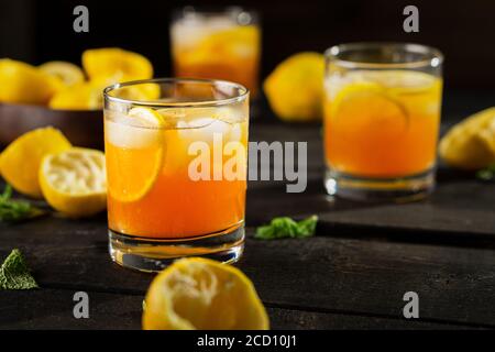 Bicchiere di tè freddo al limone fatto in casa su sfondo scuro. Una rinfrescante bevanda estiva fatta di limone spremuto a mano fresco mescolato con tè nero freddo, ghiaccio e zucchero Foto Stock