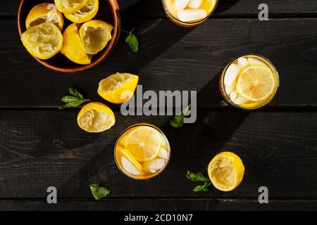 Tè freddo al limone dall'alto su sfondo scuro. Una rinfrescante bevanda estiva fatta di limone spremuto a mano fresco mescolato con tè nero freddo, ghiaccio e zucchero. Ad Foto Stock