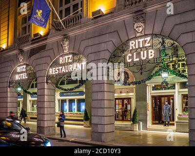 The Ritz Hotel, Ritz Club e Ritz Restaurant, insegne iconiche in luci al tramonto della sera, con decorazioni natalizie e portiere in uniforme a Christmas Piccadilly Londra Regno Unito Foto Stock